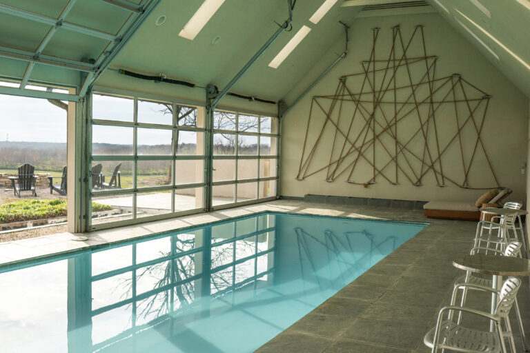 An indoor pool with three large overhead doors that lead outside
