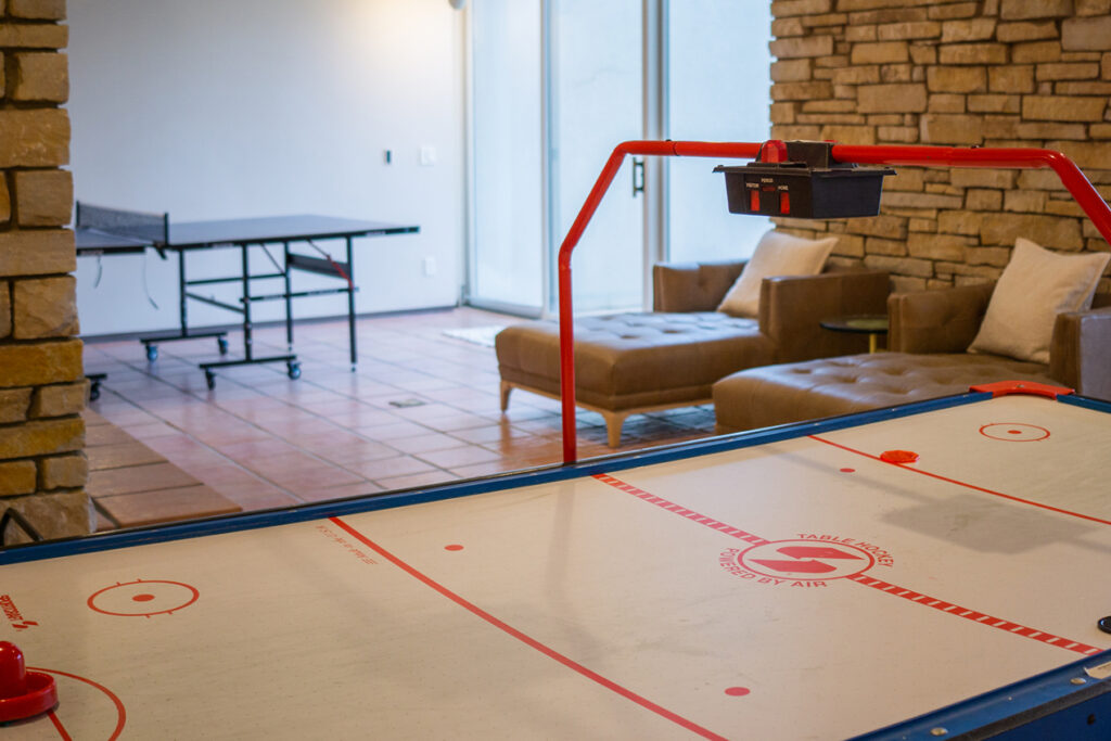 An air hockey table with a ping pong table in the background.